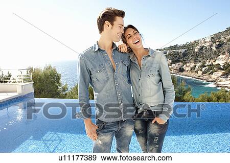Stock Photo - Smiling couple standing beside pool. Fotosearch