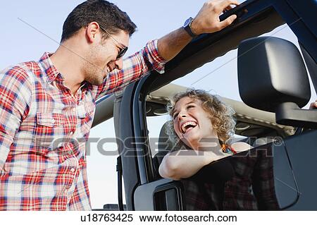 Stock Photography - Smiling couple talking near jeep. Fotosearch