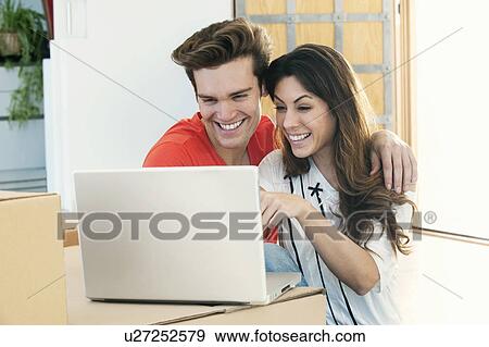 Stock Photo - Smiling couple using laptop together. Fotosearch