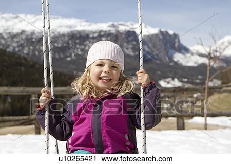 Stock Image - Smiling girl playing on swing outdoors. Fotosearch