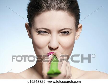 Stock Photo - Smiling woman blowing noisemaker. Fotosearch