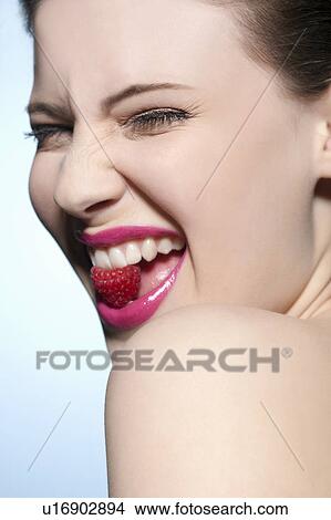 Smiling woman eating a raspberry View Large Photo Image Picture - Smiling woman eating a raspberry. Fotosearch