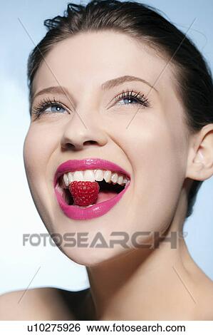 Smiling woman eating a raspberry View Large Photo Image Stock Photograph - Smiling woman eating a raspberry. Fotosearch