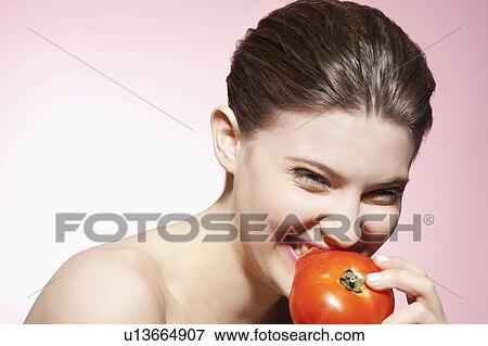 Smiling woman eating a tomato View Large Photo Image Stock Photo - Smiling woman eating a tomato. Fotosearch
