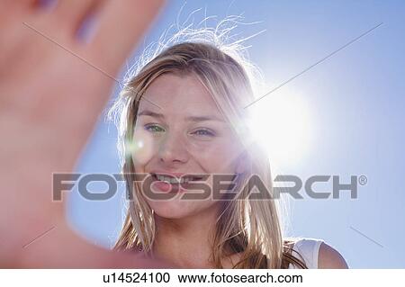 Stock Image - Smiling woman holding up hand. Fotosearch