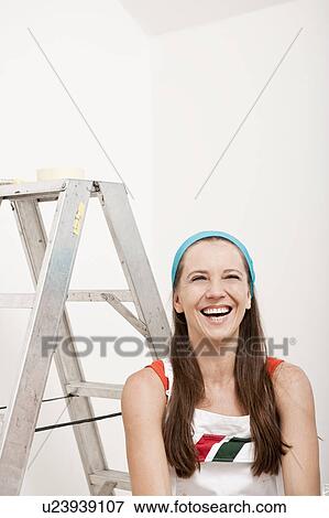 Stock Photo - Smiling woman sitting by ladder. Fotosearch