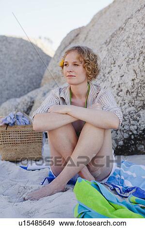 Stock Photo - Smiling woman sitting on beach. Fotosearch