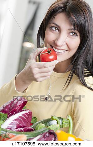 Stock Photography - Smiling woman with tomato and vegetables. Fotosearch