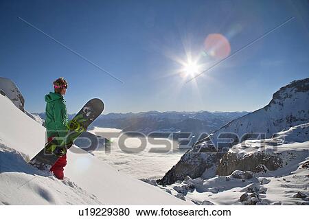 Stock Image - Snowboarder looking from mountain top. Fotosearch