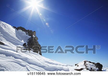 Stock Photography - Sun over snow covered mountain. Fotosearch