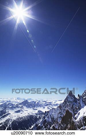 Stock Image - Sun over snow covered mountains. Fotosearch