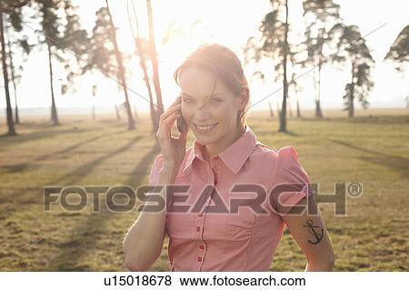 Stock Photo - Tatooed Women in Nature with Cellphone. Fotosearch