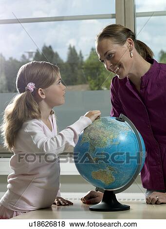 Stock Photo - Teacher and girl with earth globe. Fotosearch
