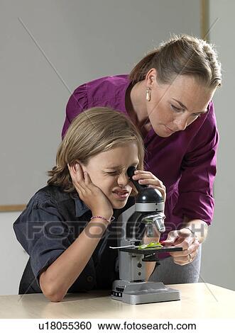 Stock Image - Teacher and student using microscope. Fotosearch