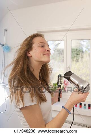 Teenage girl blow drying her hair View Large Photo Image Stock Photograph - Teenage girl blow drying her hair. Fotosearch