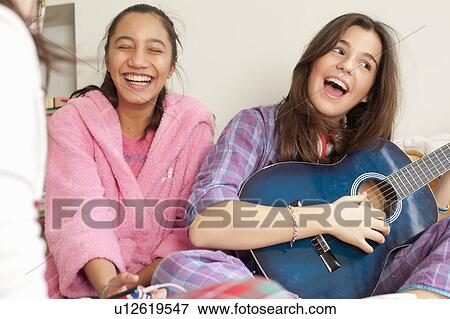 Stock Photo - teenage girl listening to music in pajamas. Fotosearch