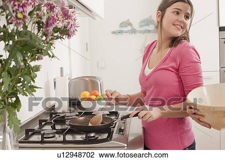 Stock Image - teenage girl making pancakes. Fotosearch
