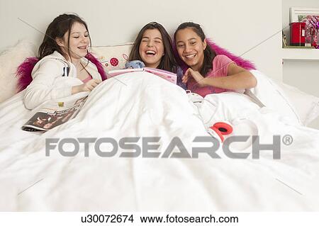 Picture - teenage girls having fun in bed . Fotosearch
