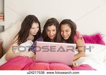 teenage girls looking at laptop in bed View Large Photo Image Stock Photo - teenage girls looking at laptop in bed. Fotosearch