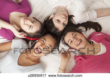 teenage girls lying on floor listening to music, smiling View Large Photo Image Stock Photo - teenage girls lying on floor listening to music, smiling. Fotosearch