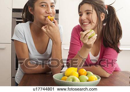 teenage girls smiling, eating fruit View Large Photo Image Stock Image - teenage girls smiling, eating fruit. Fotosearch