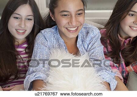 Stock Photo - teenage girls watching tv on sofa. Fotosearch