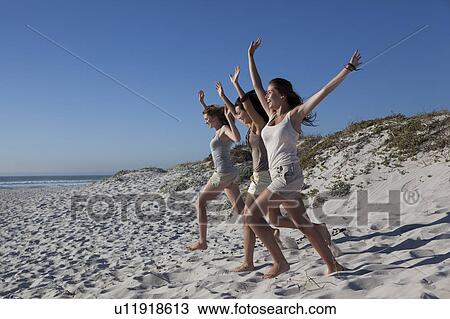 Stock Image - Three girls running down hill. Fotosearch