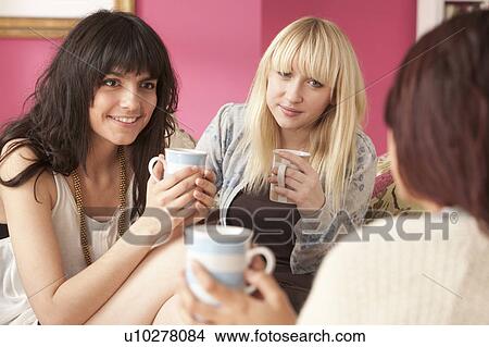 Three young women chatting with mugs View Large Photo Image Picture - Three young women chatting with mugs. Fotosearch