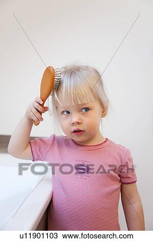 Stock Image - Toddler girl brushing her hair. Fotosearch