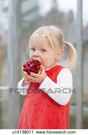 Stock Image - Toddler girl eating fruit cake. Fotosearch