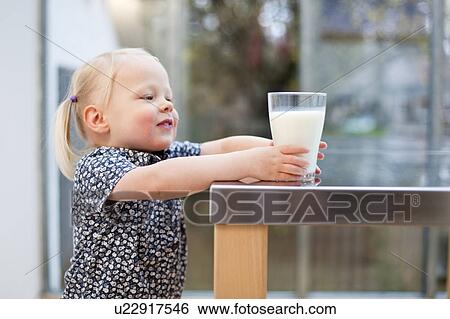 Toddler girl holding glass of milk View Large Photo Image Stock Photograph - Toddler girl holding glass of milk. Fotosearch