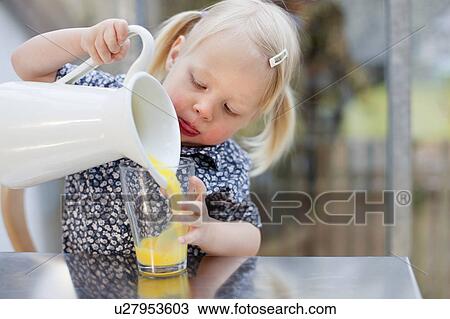 Stock Image - Toddler girl pouring glass of juice. Fotosearch