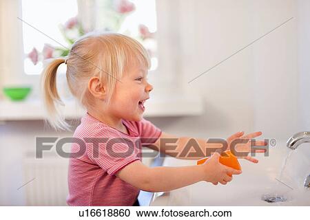 Stock Image - Toddler girl washing her hands. Fotosearch