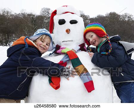 Stock Image - Two boys hugging a snowman. Fotosearch