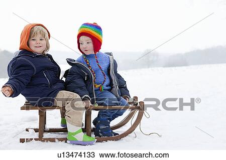 Stock Image - Two boys on a sledge in the snow. Fotosearch