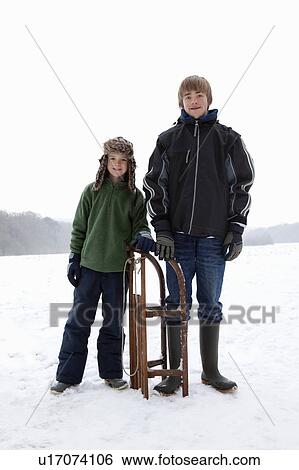 Two boys standing next to a sledge View Large Photo Image Stock Photograph - Two boys standing next to a sledge. Fotosearch