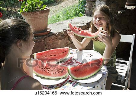 Two girls eating watermelon View Large Photo Image Stock Photography - Two girls eating watermelon. Fotosearch