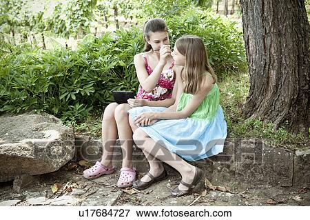Two girl's playing under a tree View Large Photo Image Stock Photo - Two girl's playing under a tree. Fotosearch