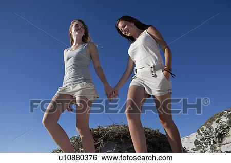 Stock Photograph - Two girls walking hand in hand. Fotosearch