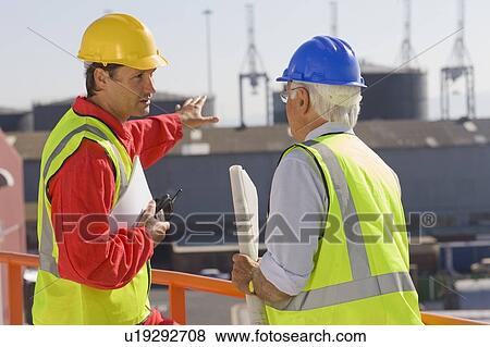 Stock Photo - Two harbour workers talking about work. Fotosearch