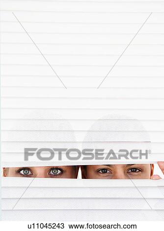 Stock Image - Two women look through blinds. Fotosearch