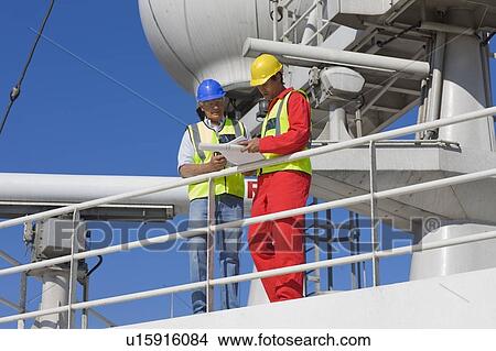Picture - Two workers standing on guardrail. Fotosearch