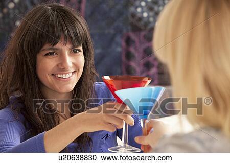 Two young women chinking glasses View Large Photo Image Stock Image - Two young women chinking glasses. Fotosearch