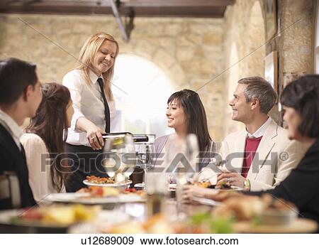 Stock Photo - Waitress serving people in restaurant. Fotosearch