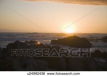 Stock Photo - Waves crashing over rocks on beach. Fotosearch