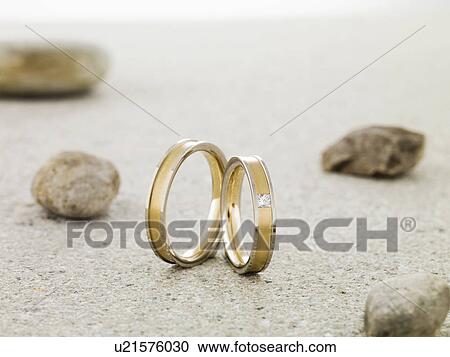 Stock Image - Wedding rings balanced on stone. Fotosearch