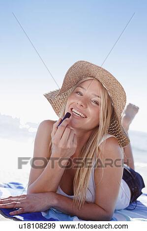 Stock Photo - Woman applying lipstick at beach. Fotosearch