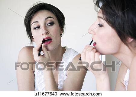 Woman applying lipstick in mirror View Large Photo Image Stock Image - Woman applying lipstick in mirror. Fotosearch