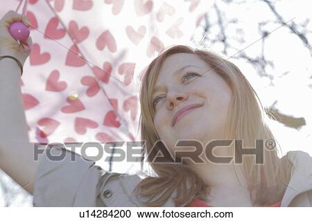 Woman carrying umbrella in park View Large Photo Image Stock Image - Woman carrying umbrella in park. Fotosearch