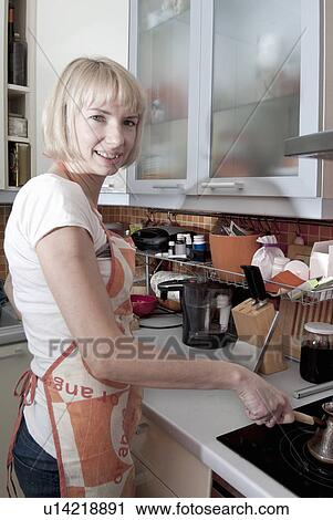 Stock Image - Woman cooking in kitchen. Fotosearch